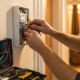 Technician performing a security system repair on a home's control panel.