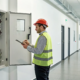 Technician conducting commercial fire alarm testing with a checklist at a control panel.