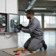 Technician inspecting an existing alarm control panel in Atlanta